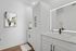 Sleek modern bathroom with elegant white cabinetry, large illuminated mirror, and stylish abstract wall art.