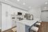 Modern kitchen with sleek white cabinetry, marble countertops, and stainless steel appliances, featuring a large island and cushioned barstools.