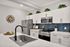 Modern kitchen with sleek stainless steel appliances, elegant white cabinetry, and a stylish navy backsplash, accented by decorative greenery and artistic wall decor.