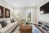 Charming living room with stylish decor, featuring a cozy sofa, elegant artwork, and a wicker coffee table, bathed in natural light.