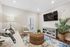 Charming living room with cozy seating, modern decor, and a large TV, highlighted by a stylish wicker coffee table and lush greenery.