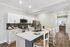 Contemporary kitchen with sleek white cabinets, modern appliances, and an inviting breakfast bar, opening into a stylish hallway.