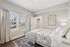 Bright and elegant bedroom with floral bedding, large windows, and chic decor, offering a cozy and inviting atmosphere.