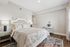Inviting bedroom with elegant white furniture and floral bedding, featuring soft lighting and a beautiful patterned rug for a cozy ambiance.