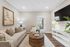 Inviting living room featuring a plush beige sofa, chic wicker coffee table, and elegant decor with natural light streaming through a glass door.
