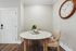 Chic corner dining nook featuring a round marble table, elegant chairs, and a vintage wall clock with natural light.