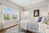 Bright and airy bedroom featuring large windows with scenic views, elegant decor, and a cozy bed with striped bedding.