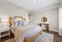 Elegant bedroom with a chic wood-framed bed, stylish lamps, and contemporary decor, radiating warmth and comfort.