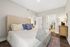Inviting bedroom with a neutral palette, featuring a plush bed with decorative pillows, elegant bedside table, and natural light streaming in for a serene atmosphere.