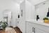 Sleek and modern bathroom with elegant white cabinetry, large mirror, and vibrant decor accents.
