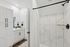 Modern bathroom featuring sleek white cabinetry, a pristine vanity, and elegant marble-tiled shower.