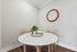 Chic dining area with a round marble table, elegant wooden chairs, and a stylish wall clock, perfect for cozy gatherings.