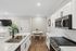 Modern kitchen with sleek white cabinetry, black fixtures, and elegant marble countertops, adjacent to a cozy dining area with natural light.