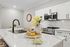 Elegant modern kitchen with sleek white cabinetry, marble countertops, and a stylish island adorned with fresh flowers and glassware.