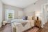 Bright and inviting bedroom with a plush bed, elegant decor, and ample natural light from large window.