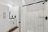 Elegant bathroom featuring white cabinetry, marble-tiled shower, and modern fixtures, offering a luxurious and serene atmosphere.
