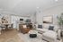 Modern open-concept living space featuring elegant white kitchen cabinets, cozy beige sectional, and stylish hardwood floors.