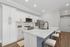 Modern kitchen with sleek white cabinets, elegant countertops, and a spacious breakfast bar with stools.