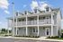 Charming two-story modern apartment complex with a spacious wrap-around balcony, surrounded by lush greenery and ample parking.