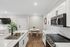Modern kitchen with sleek white cabinetry and stainless steel appliances, featuring a chic marble countertop and inviting dining area.
