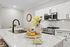 Elegant modern kitchen with sleek white cabinetry, stainless steel appliances, and a chic marble countertop featuring a stylish floral arrangement.