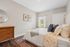 Charming bedroom with elegant decor featuring a cozy bed, modern wooden dresser, and ample natural light.