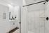 Elegant bathroom with marble tile shower, sleek black fixtures, and white cabinetry for a modern touch.
