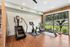 Bright and modern fitness room featuring state-of-the-art exercise equipment, with a scenic view of lush greenery through large windows.