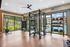 Modern fitness center with floor-to-ceiling windows offering a scenic pool view, featuring premium exercise equipment and vibrant decor.