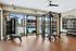 Bright and spacious gym with modern equipment, overlooking a pristine outdoor pool and lush surroundings.