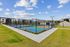 Modern apartment complex featuring vibrant sports courts, surrounded by lush greenery and clear skies.
