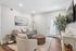 Modern living room featuring a cozy gray sofa, elegant armchair, and stylish wicker coffee table, complemented by bright decor and a large plant for a refreshing ambiance.
