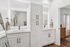 Modern bathroom featuring dual sinks with sleek black faucets, elegant white cabinetry, and stylish mirrors with ambient lighting.
