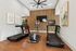 Modern gym with two treadmills, an elliptical, wooden flooring, and stylish artwork, offering a sleek workout environment.