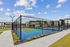Vibrant apartment complex featuring a modern tennis court under a clear blue sky, surrounded by lush greenery and contemporary architecture.