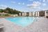 Luxurious apartment complex with a stunning outdoor pool, surrounded by spacious lounge chairs and modern architecture.