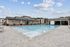 Luxurious outdoor swimming pool area featuring modern cabanas and sun loungers, set against a clear blue sky.