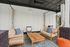 Chic outdoor seating area with modern wood furniture, plush cushions, and a vibrant orange pouf, perfect for relaxation.