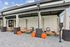 Chic outdoor seating area with stylish wooden furniture, cozy cushions, and vibrant orange poufs, perfect for relaxation.