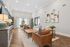 Elegant living room with modern decor, featuring leather armchairs, a cozy sofa, and large windows offering a bright, inviting atmosphere.