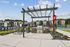 Inviting outdoor community area with a modern pergola, BBQ grill, and picnic spot, set against a backdrop of well-maintained apartments and a sparkling pool.