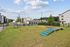 Spacious and inviting dog park with agility equipment, surrounded by modern apartment buildings under a clear blue sky.