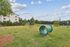 Expansive outdoor dog park with agility equipment, lush green lawn, and serene natural surroundings.