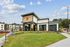 Modern apartment complex with a sleek architectural design, manicured lawns, and vibrant landscaping under a clear blue sky.