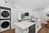 Modern apartment kitchen with sleek white cabinetry, integrated appliances, and in-unit washer and dryer, featuring stylish decor in an open-concept living space.