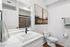 Elegant bathroom with sleek white fixtures, modern artwork, and ambient lighting.