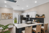 Modern kitchen with sleek black backsplash, marble countertops, and cozy wicker bar stools. Stainless steel appliances and elegant decor enhance the inviting space.