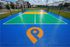 Vibrant outdoor sports court with colorful markings, perfect for recreational activities, surrounded by lush greenery and modern apartment buildings.
