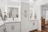 Elegant bathroom with dual vanity sinks, sleek white cabinetry, and modern mirrors with integrated lighting.