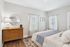 Cozy bedroom with stylish decor, featuring a wooden dresser, elegant mirror, and soft, natural lighting.